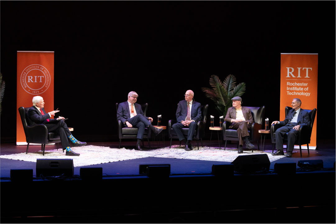 5 men sit on stage for an interview