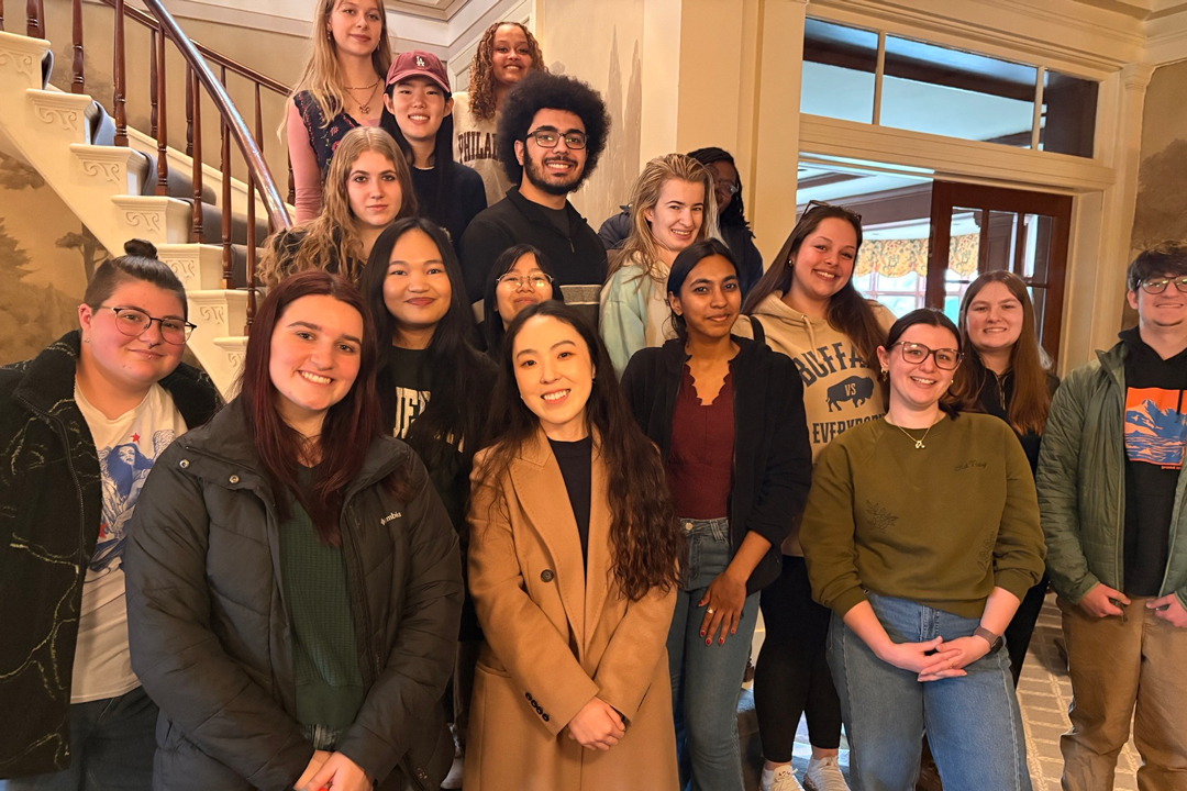 Group of students and professor pose on stairway of event venue