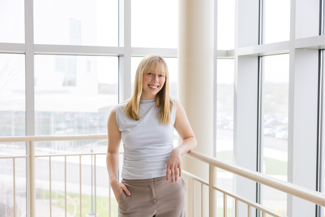 a woman with blonde hair stands in a brightly lit light atrium wearing neutral colored clothes