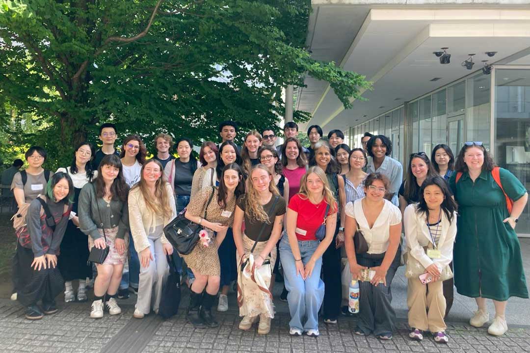 A group of students posing outside in front of a building with trees in the background