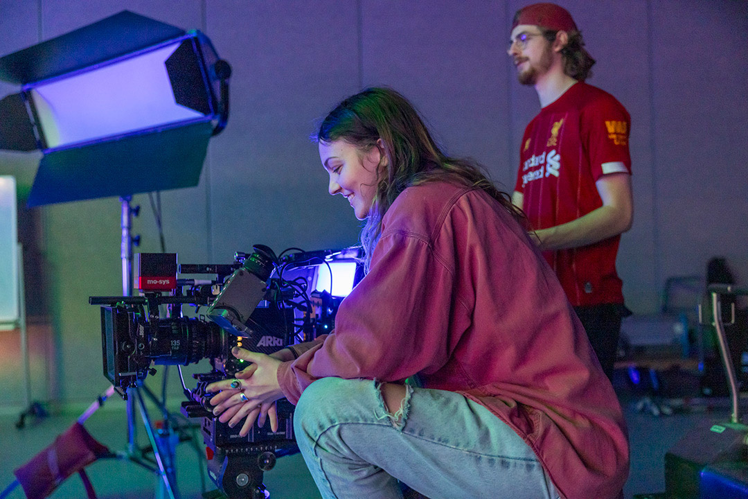 two students work behind a camera in a film studio