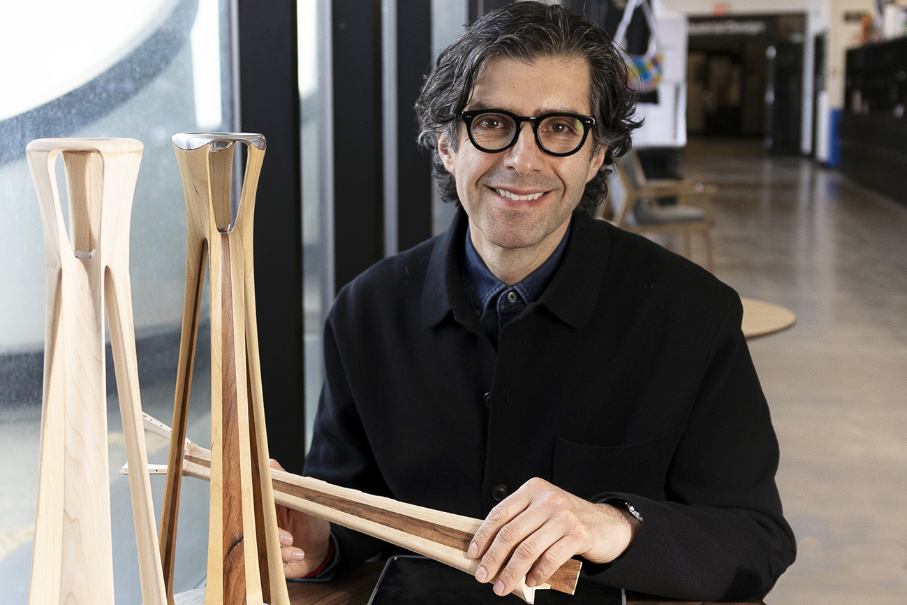 Alex Lobos sits next to tabletop wood sculptures in the industrial design studio.