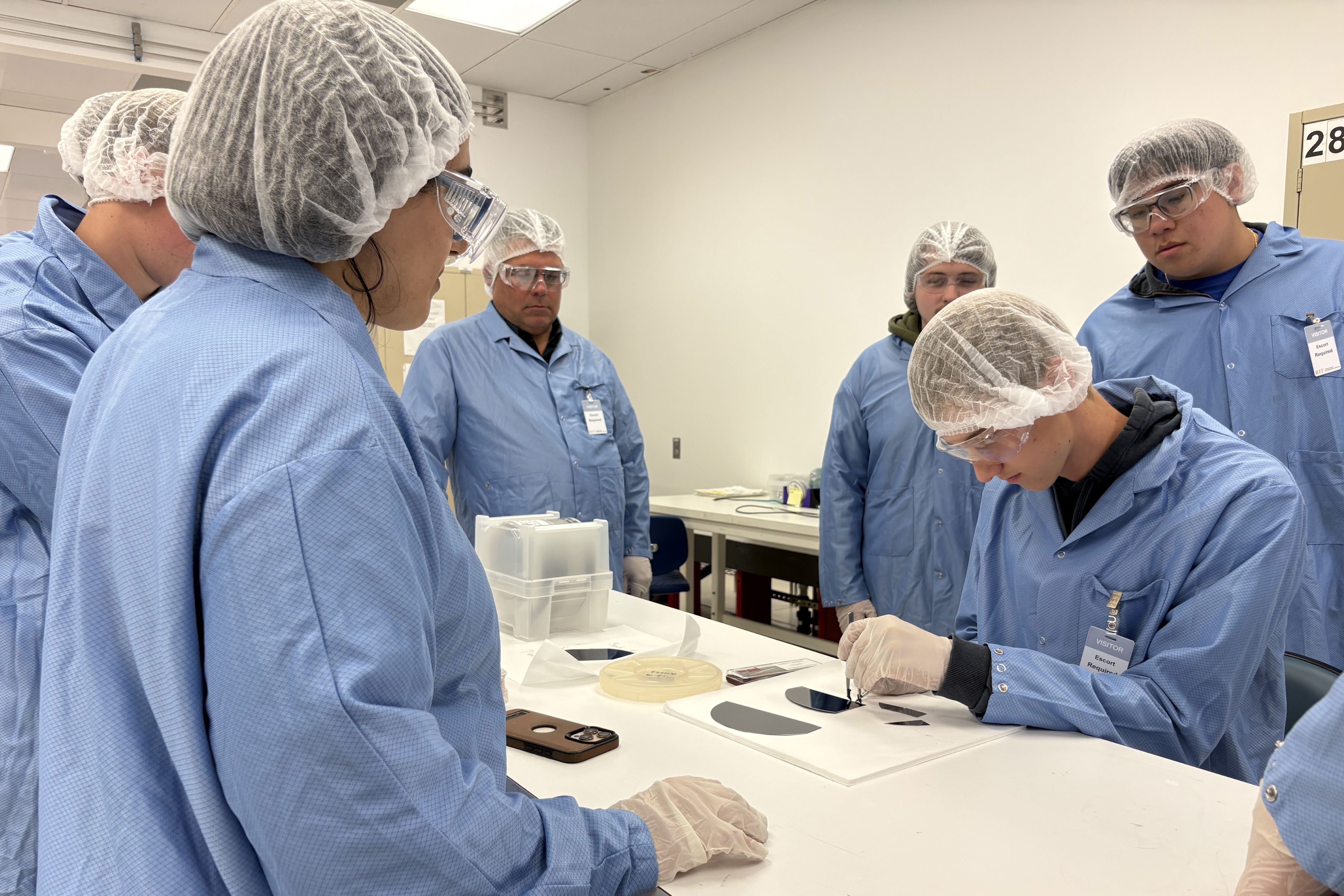 A high school student cleaves a silicon wafer while a Ph.D. student supervises in the RIT Semiconductor Nanofabrication Lab.