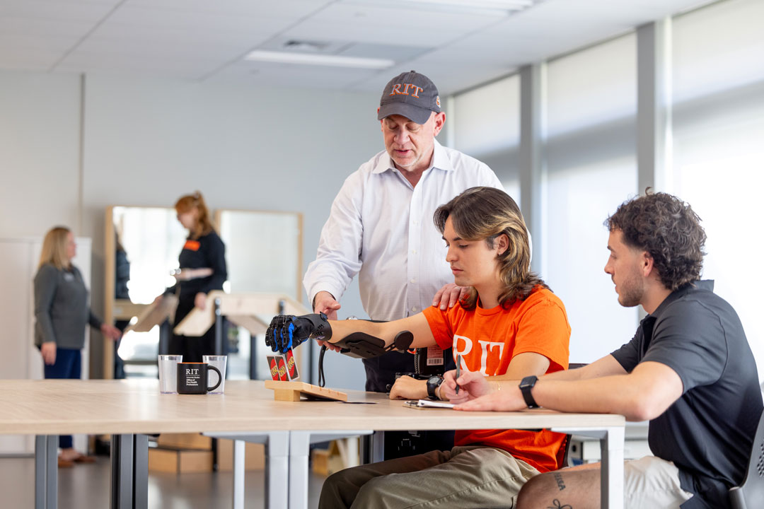 Joshua Luciano, right, shows new ways to apply design interventions that support movement and independence. Stephen Van Lew, left, assistant professor, demonstrates how to use a rehabilitation glove. 