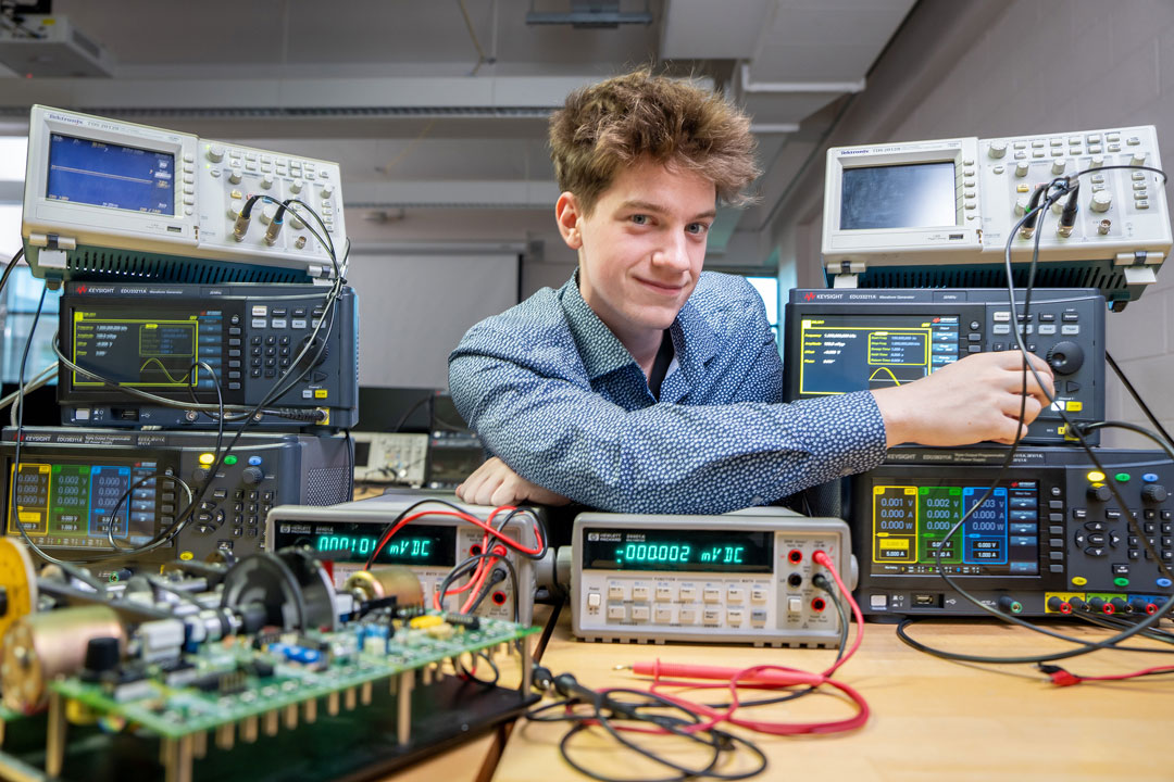 aiden morris sits at a table full of electrical engineering tools