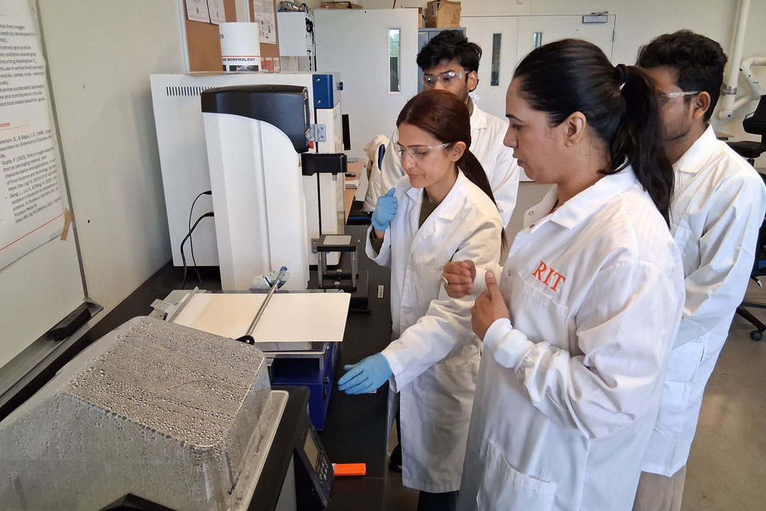'From left, Ayyuce Guzide Teke, Balaveera Srinivasaguru, and Victor Immanuel, students in the Food Packaging Lab, developed new barrier materials made of starch to protect paperboard packaging with Assistant Professor Sneh Bangar (foreground). '