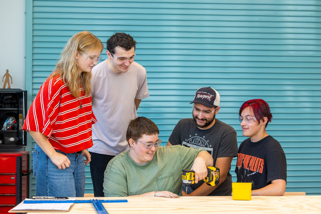 a person offers students an up-close look at some of the set pieces they are building for the upcoming production 
