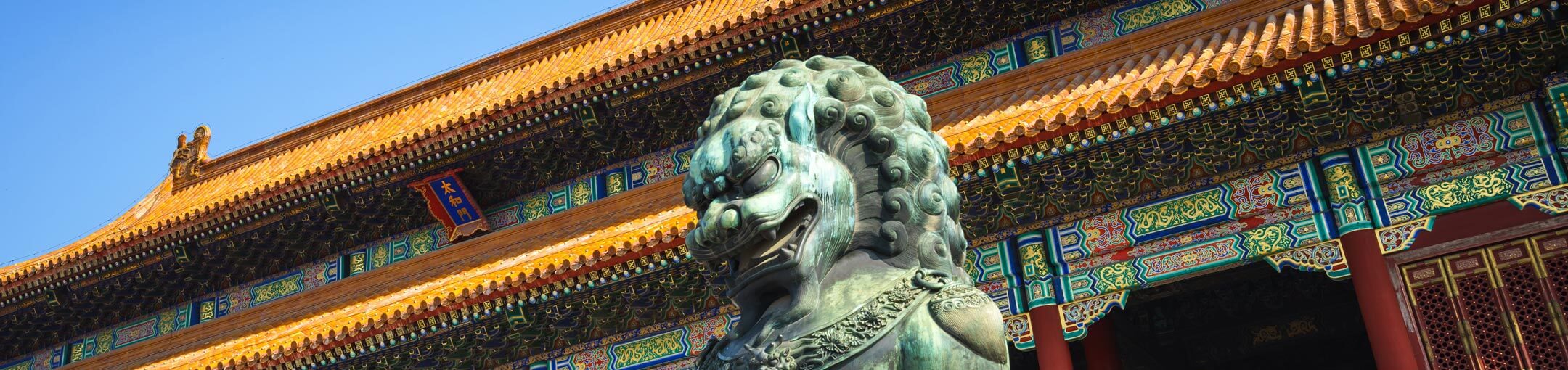 Ornamental Chinese building with lion statue in front of it.