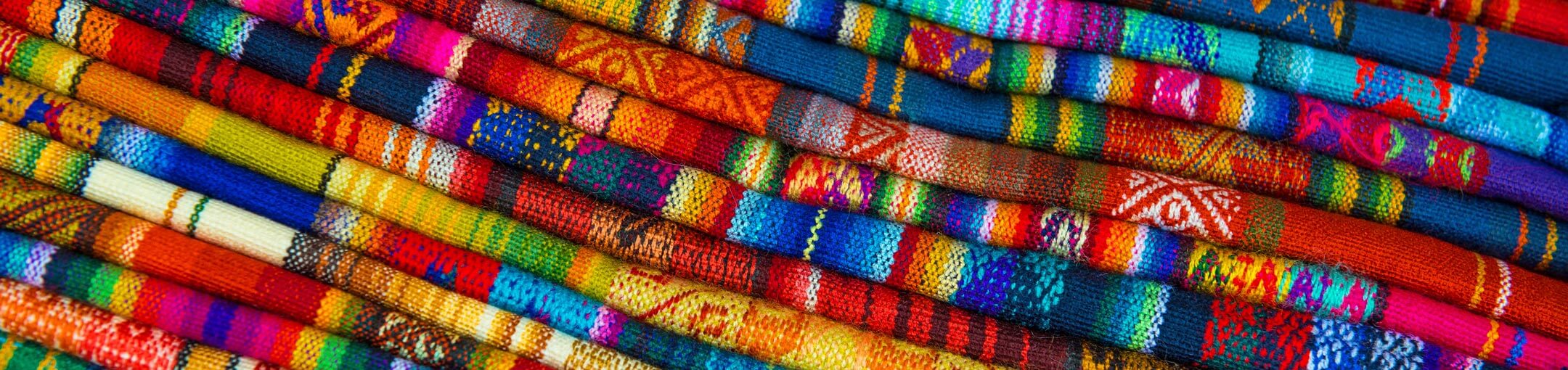 Close up of many different, colorful knit fabrics.