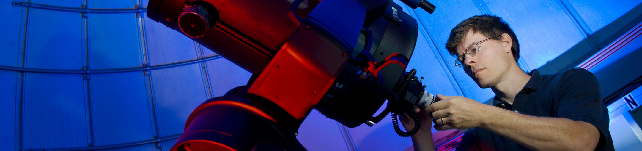 Man working on a large telescope.