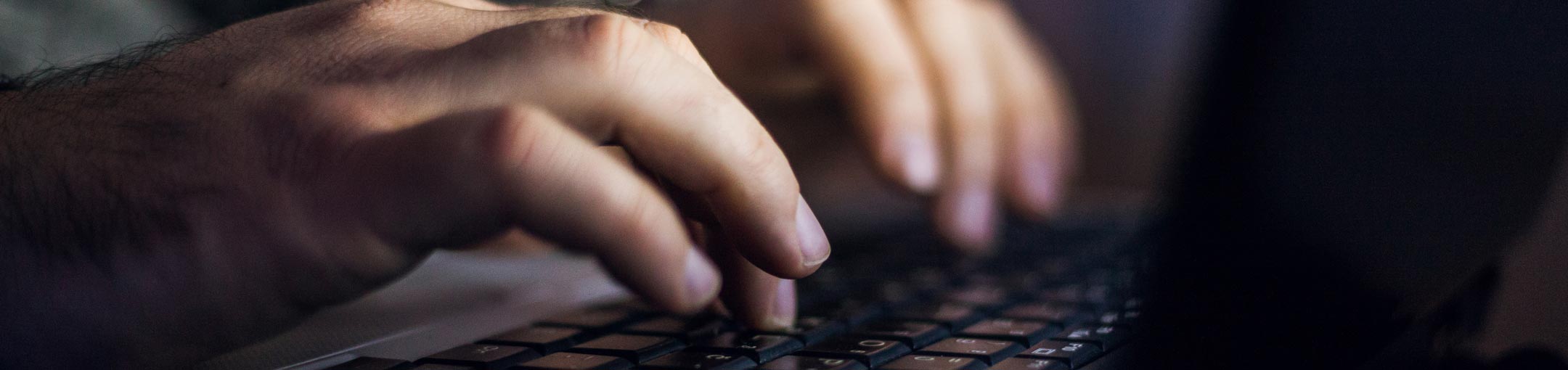 Close up of hands typing on laptop keyboard.