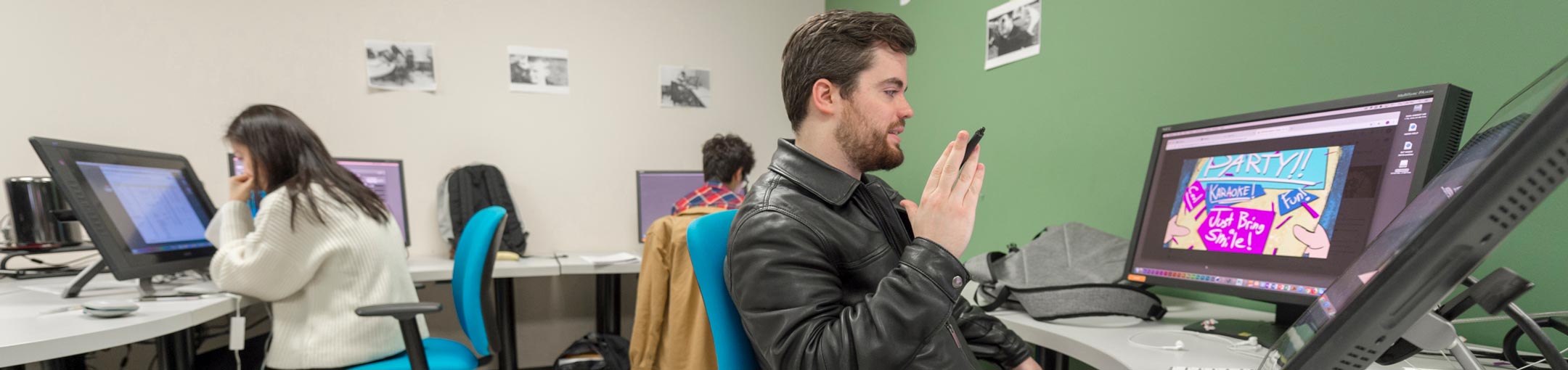Student sit in a lab in front of large touchscreen monitors