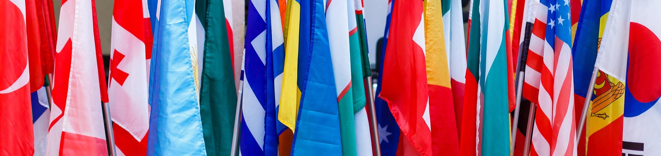 Close up of several different country flags on poles.
