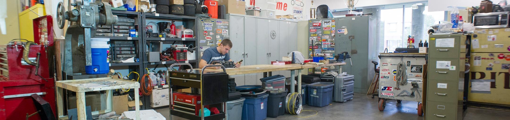 A wide angle photo of a workshop with a student sitting at a workbench.