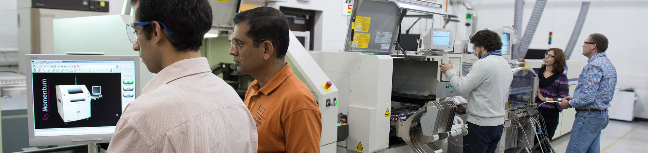 People stand at large machinery with displays.