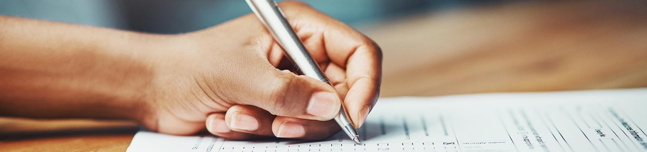 Extreme close up of a hand holding a pen checking  a box on a form.