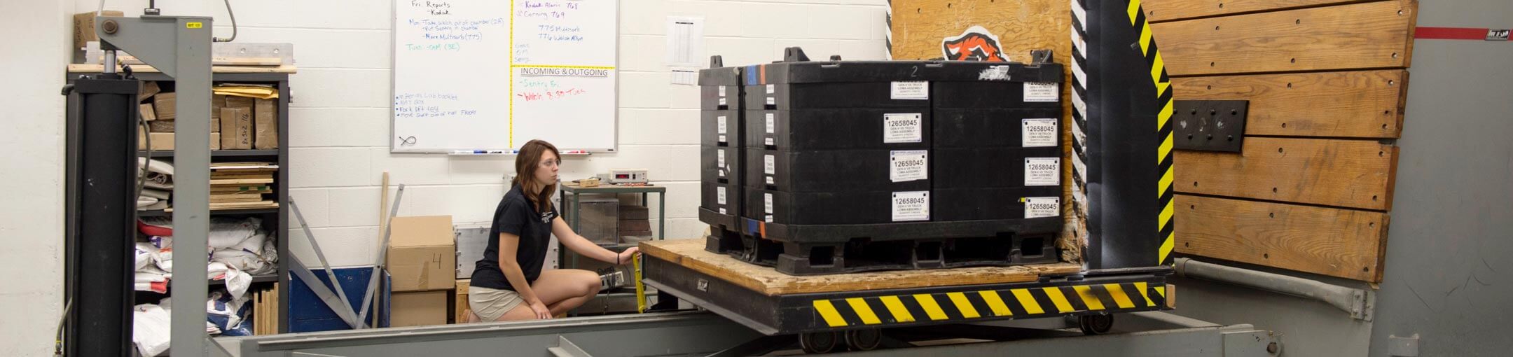 A student sits in front of a palette of boxes.