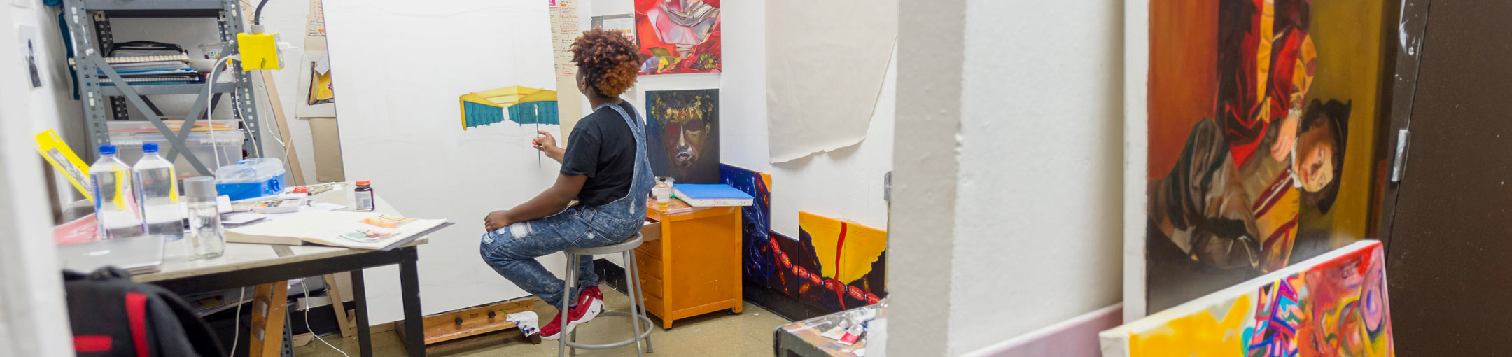 In a studio space, a student works on an architectural painting.