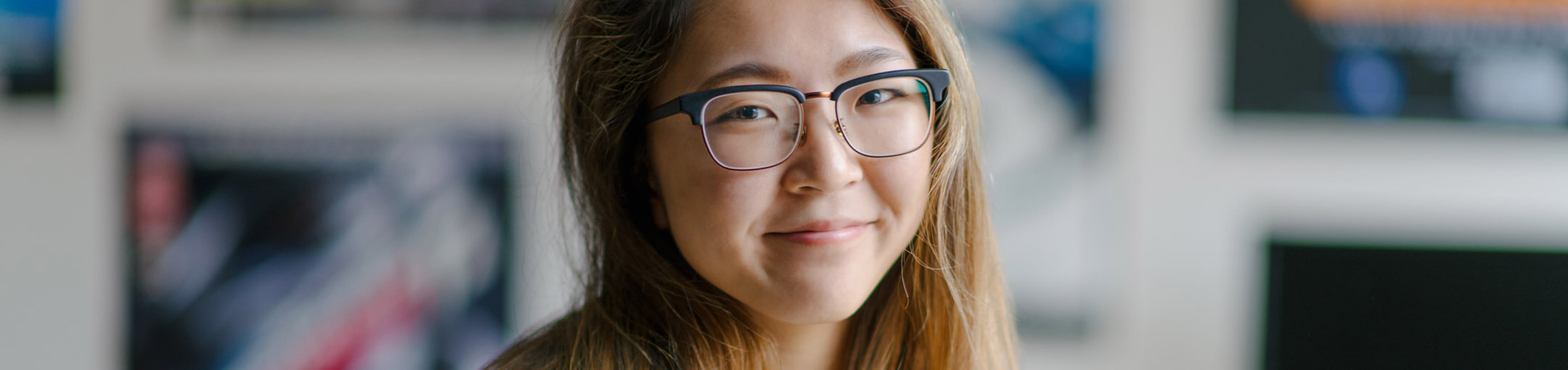 Portrait of a long-haired student wearing glasses.