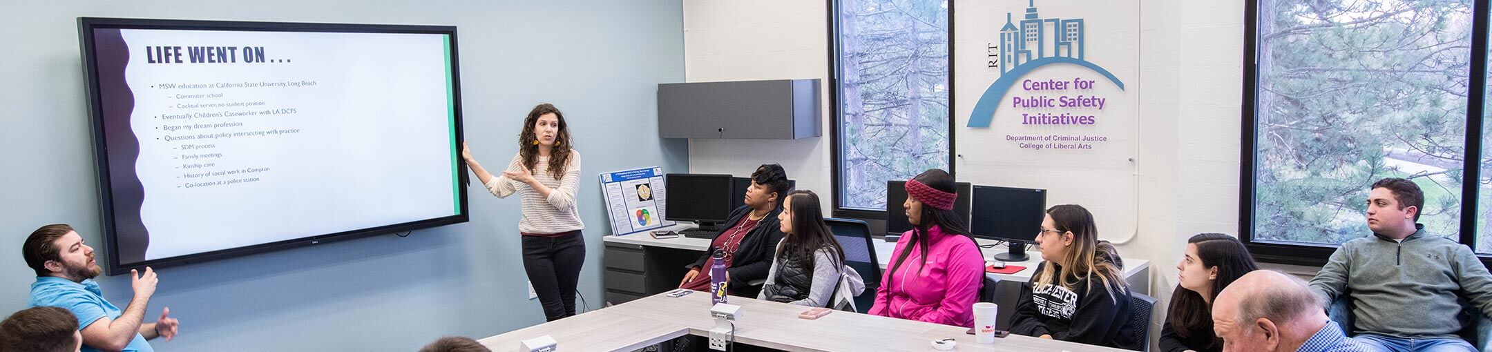 Class sits around a square table watching a presentation from the Center for Public Safety Initiatives.