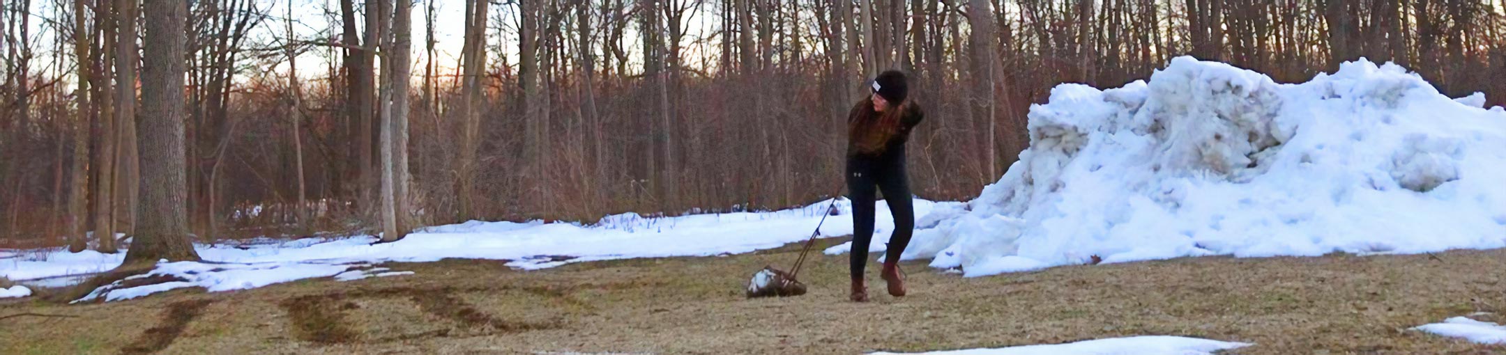 Student carves line art into the wintry ground.