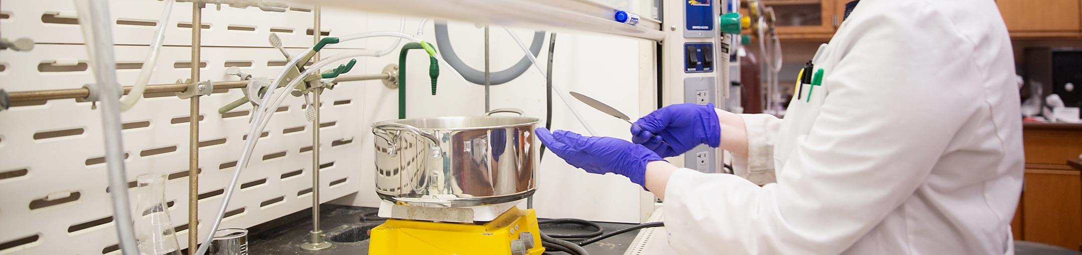 Student with purple gloves working in a lab.