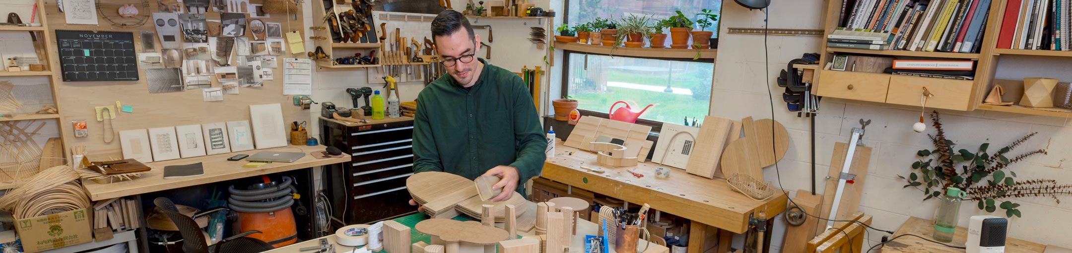 Man holds pieces of wood in wood studio.