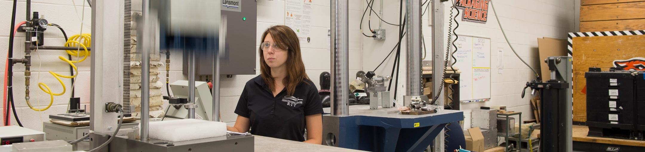 A student works with packaging equipment in a lab.