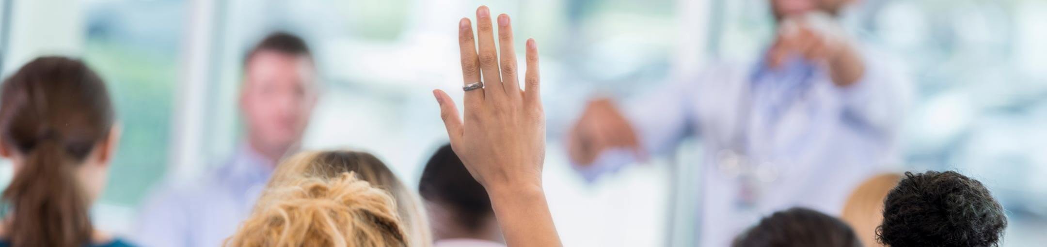 Close up of a hand raised in a classroom.