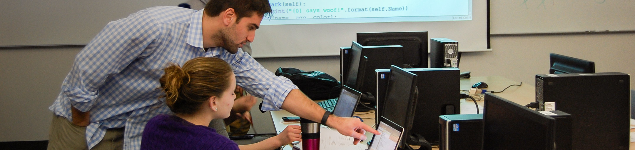 Professor helping a student at a computer in a lab.