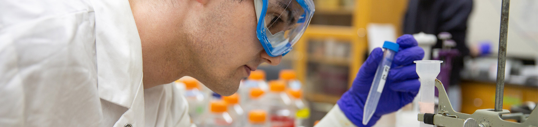 Student looking at a vial in a lab.