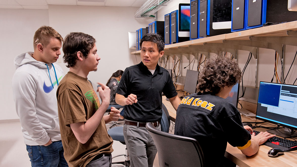 Several people talking and working in a computer lab.