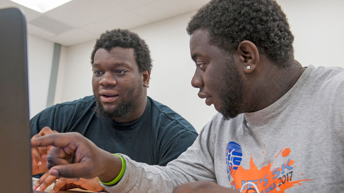 Two students pointing at a screen.