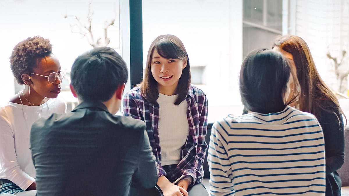 A group of students sit in a circle chatting.