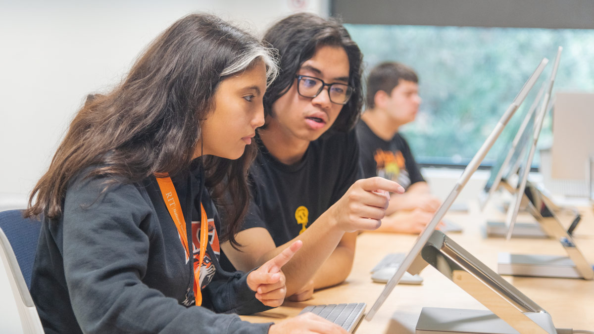 Two students work at a computer.