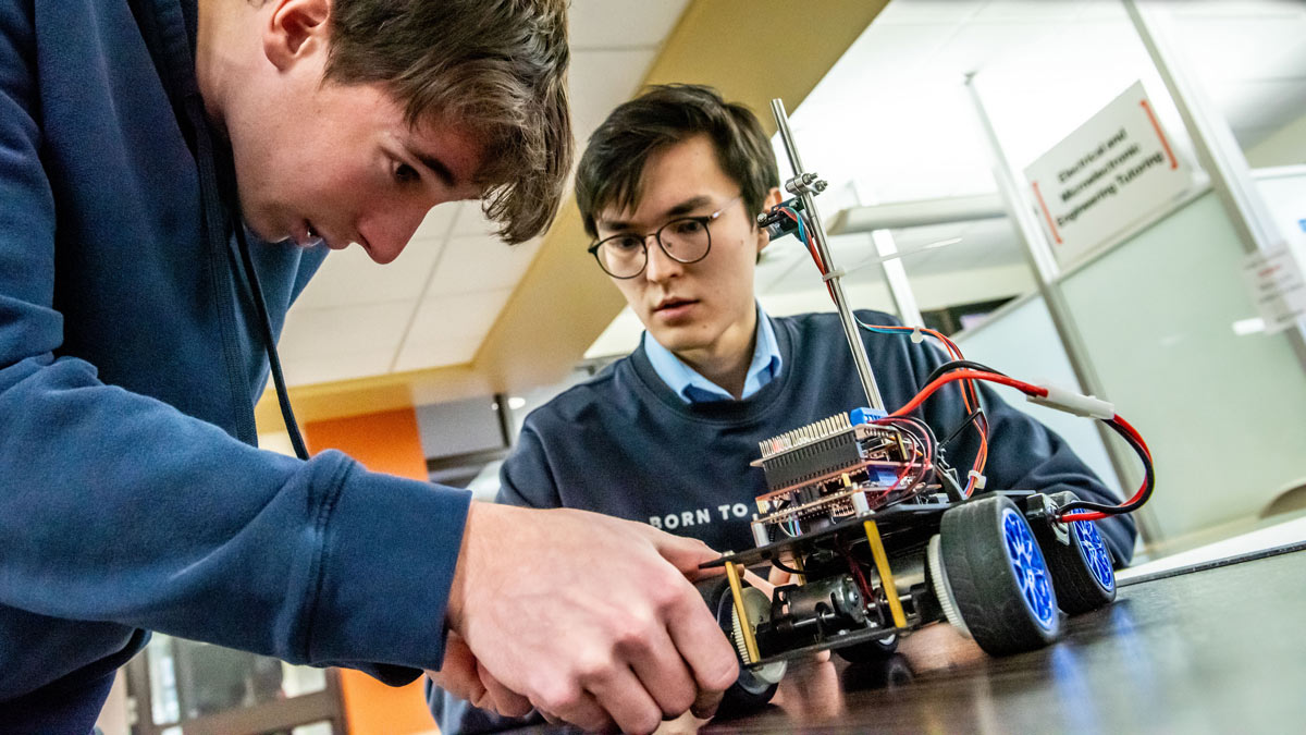 Two students work on an electronic car.