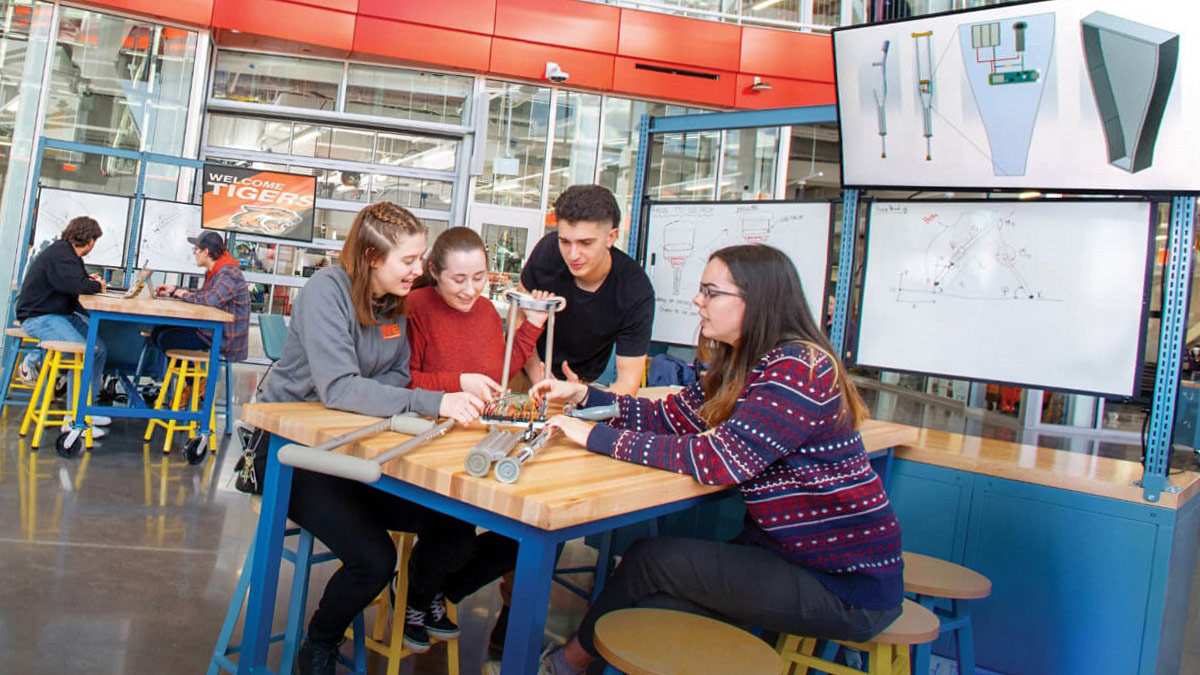 Students sit at a table working on some sort of smart crutch.
