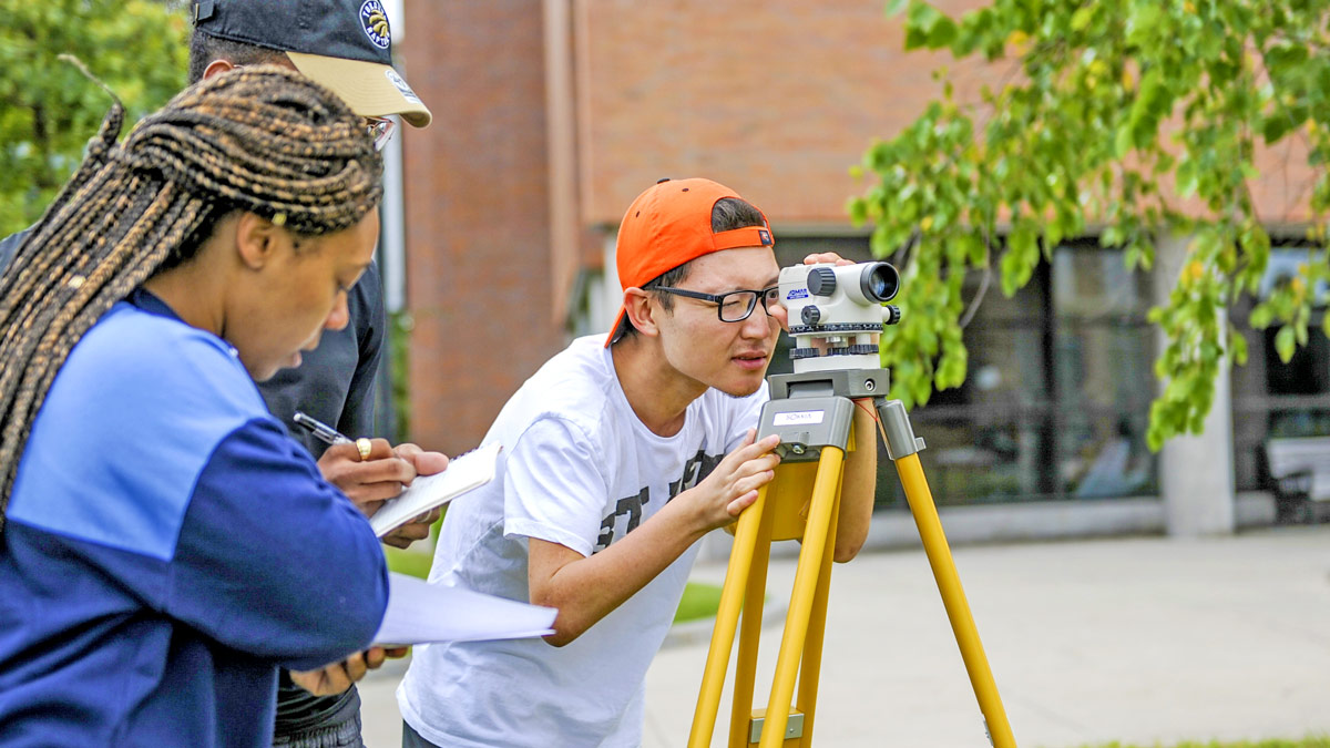 Students work with surveying equipment.