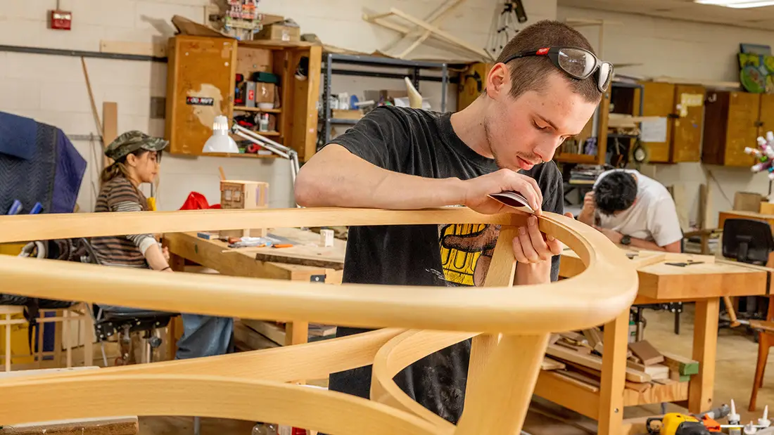 Man wearing safety glasses on his head while sanding the top of a table