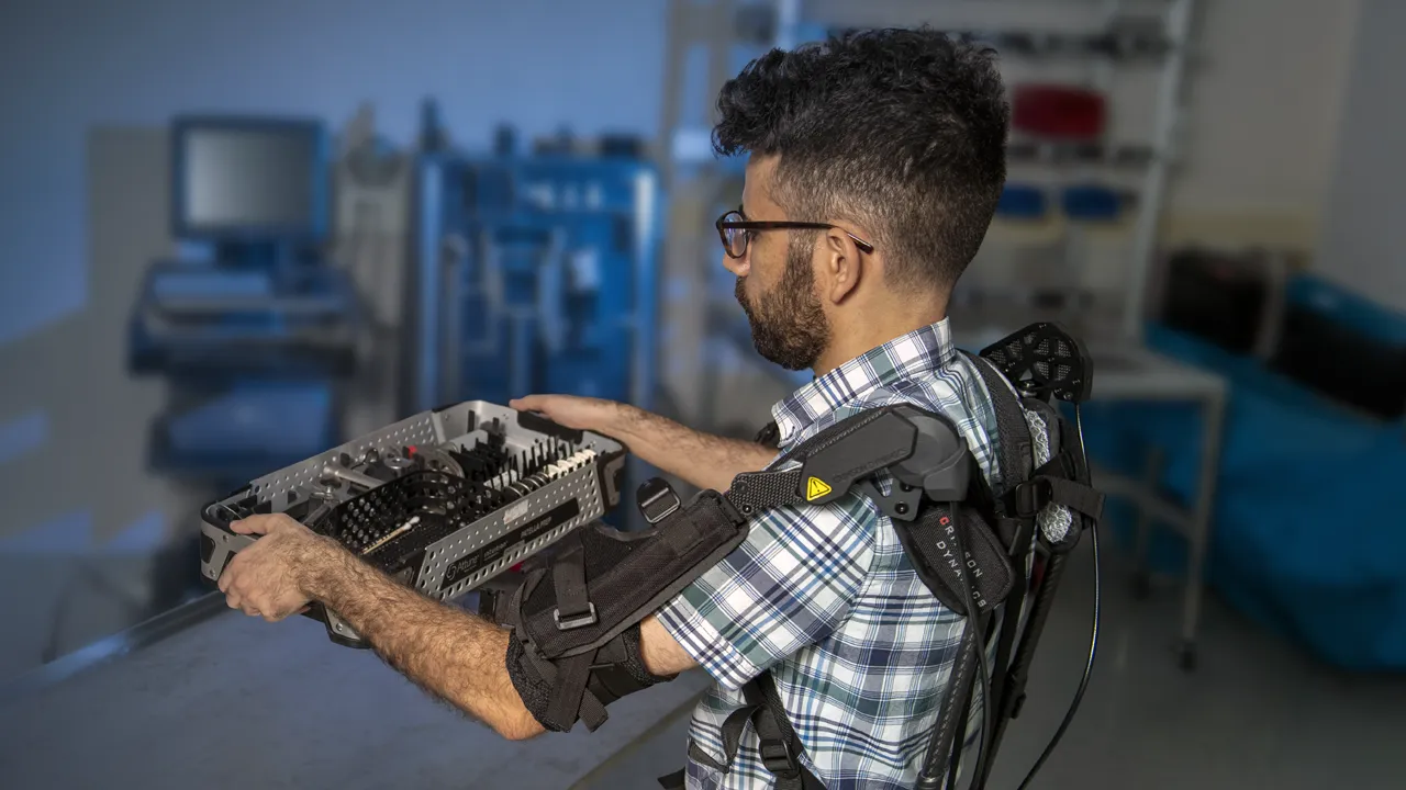 A student wears a back device to hold a heavy object.
