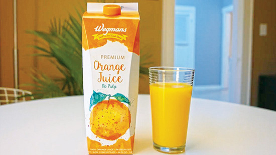 Half-gallon container of orange juice next to glass 3/4 full of juice