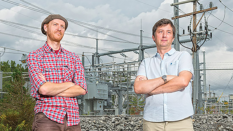 Researchers standing in front of an electrical grid