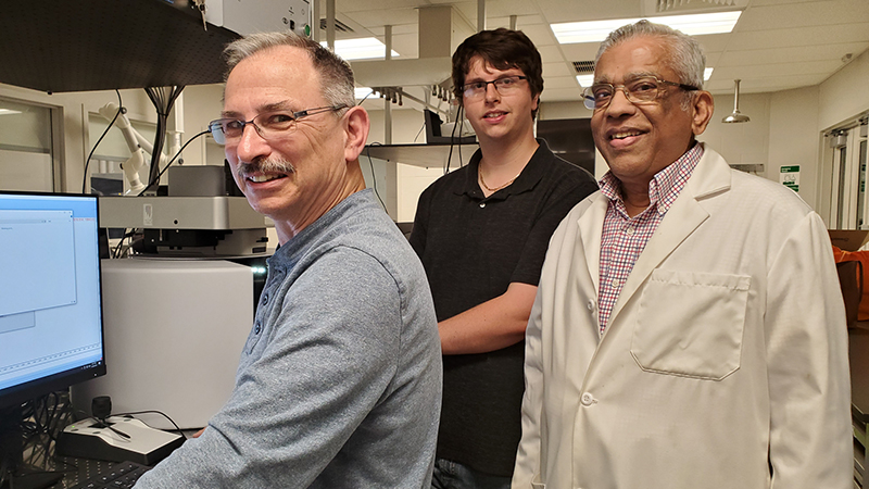 student standing with faculty and staff member in lab