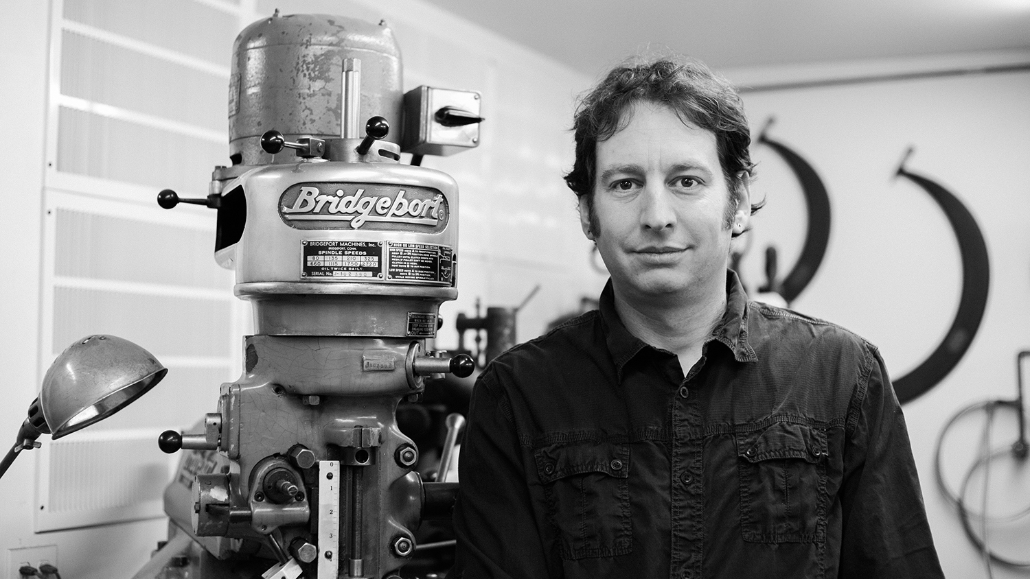 Peter Harrison stands next to a machine in his studio, where he creates unique furniture design.