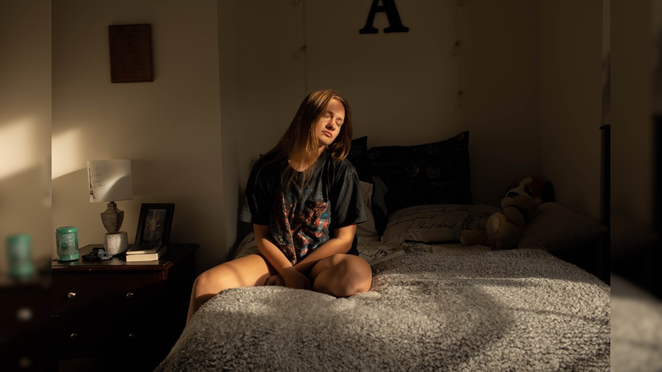 A girl sits on a bed. The photo is part of the 2020 senior fine art photography gallery exhibition.