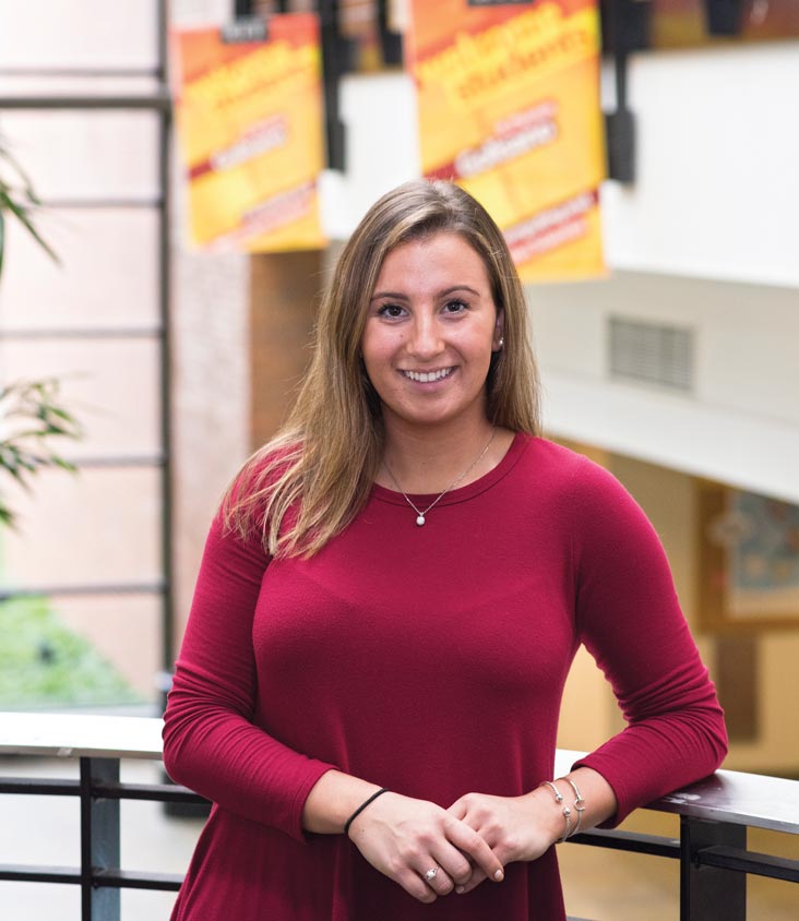 Emily Mills stands in the lobby of the Golisano College of Computing and Information Sciences.