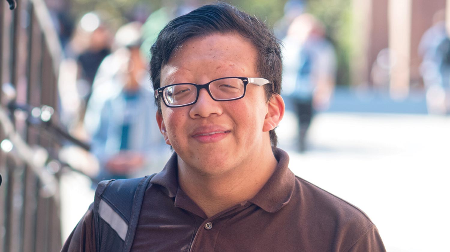 Eric Tong stands outside near a railing.