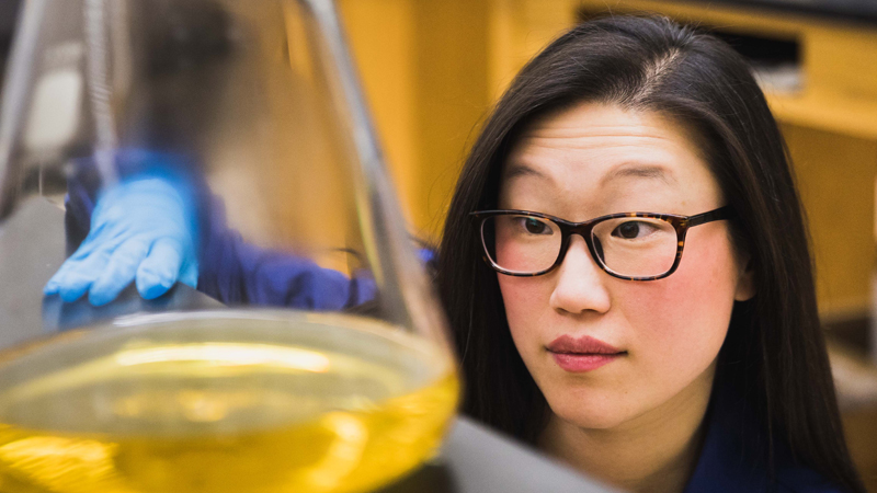 female professor looking at a beaker in a research lab