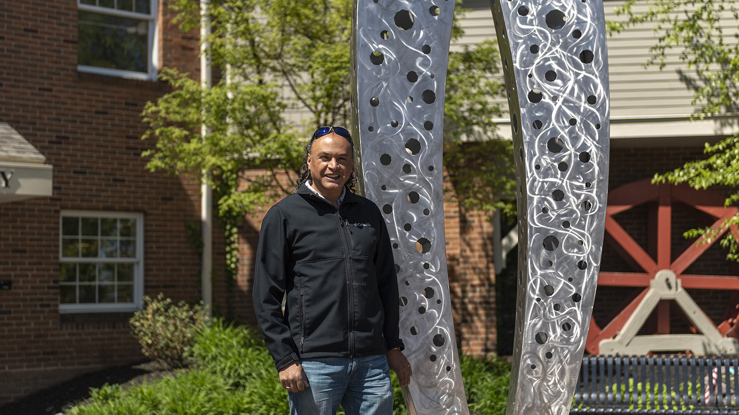 Carlos Caballero-Perez stands next to the public sculpture he created in Fairport.