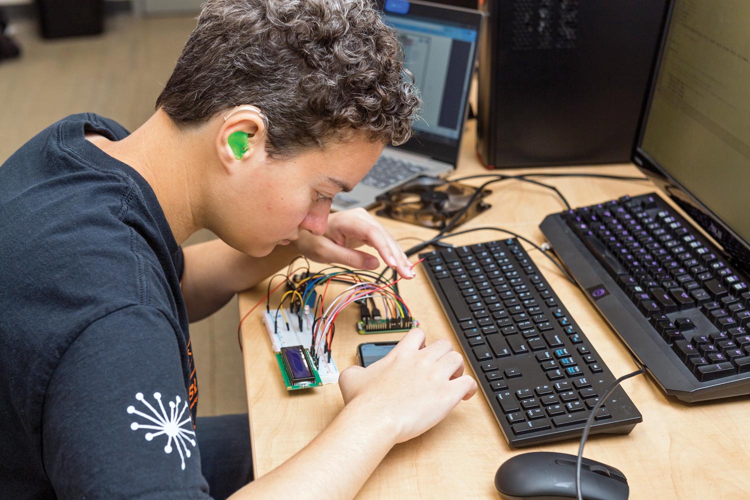 A student works at a computer developing a mobile app for a smart phone.